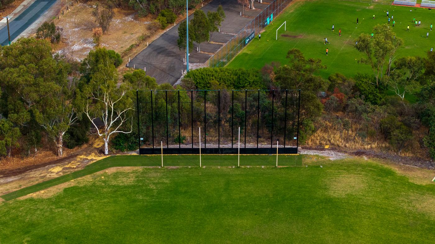 Aerial view of a tall black AFL back net behind the goals at a suburban oval